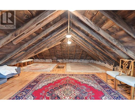A large, open attic space with wooden beams and a rug on the floor.