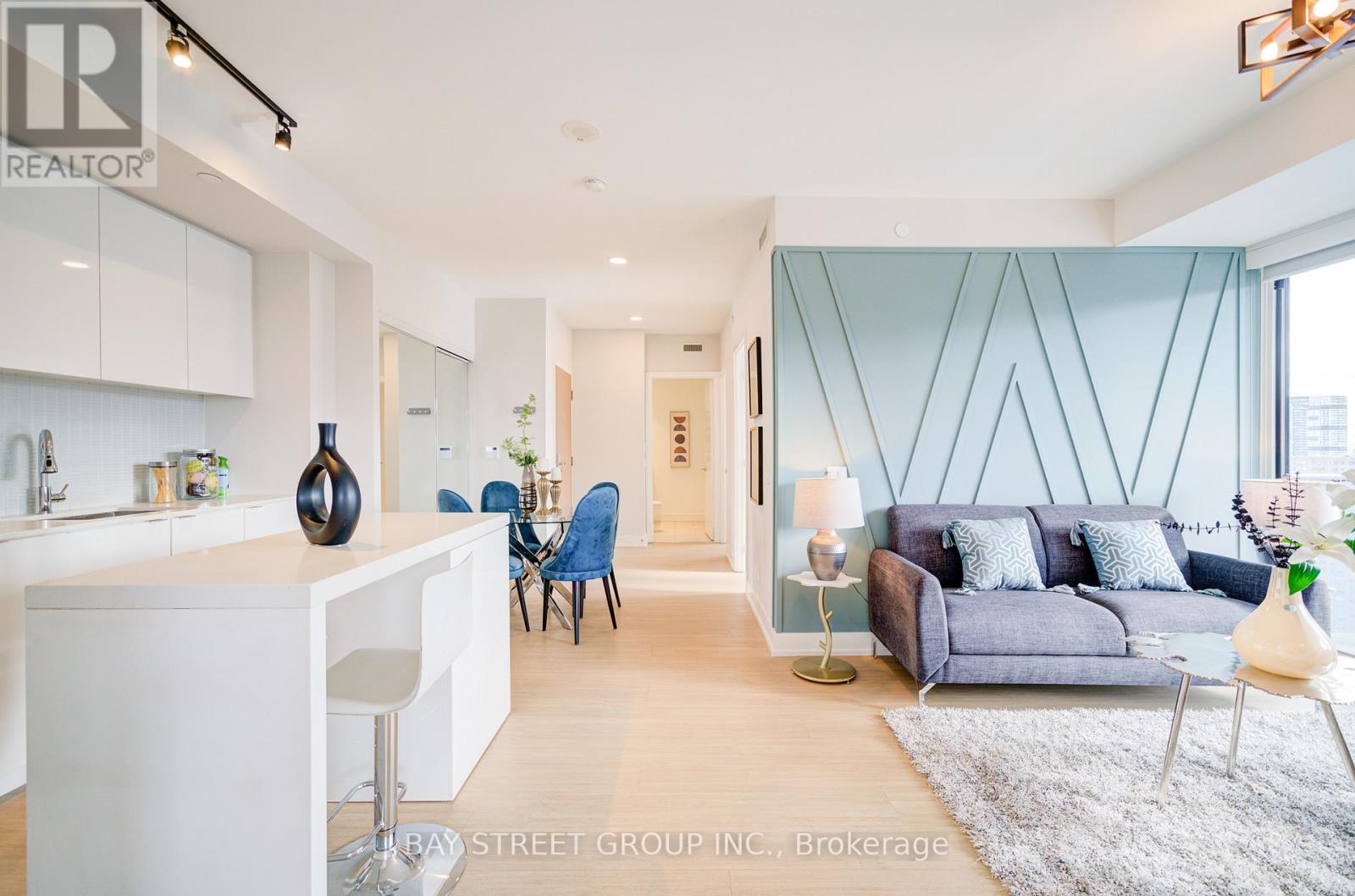 A modern living room with a kitchen area in the background.