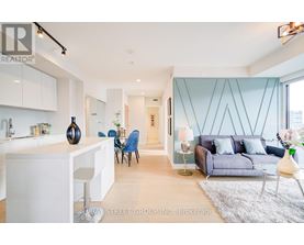 A modern living room with a kitchen area in the background.