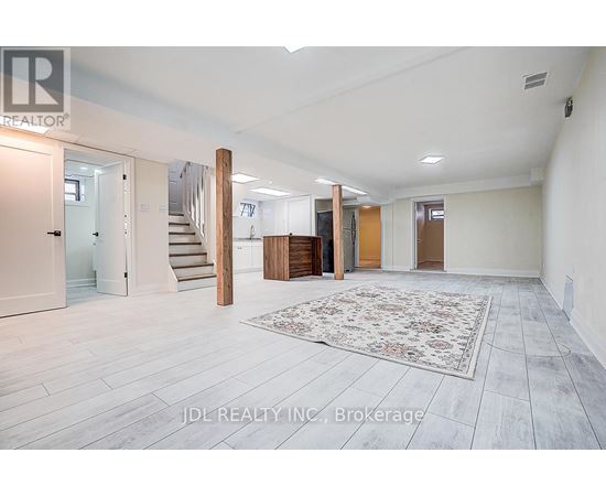 A spacious room with a staircase and a rug in the center.