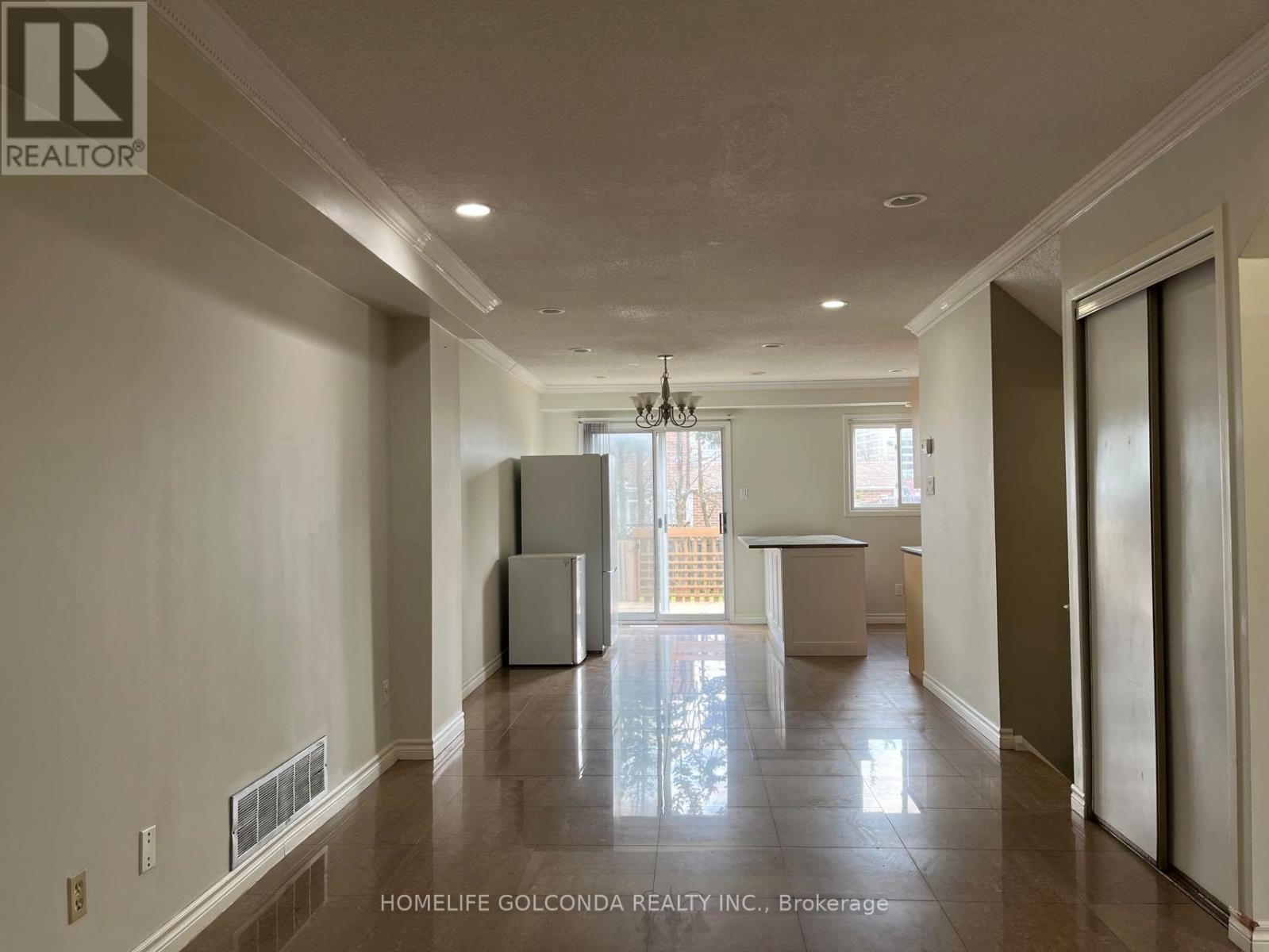 A spacious, empty room with a refrigerator and a table in the middle.