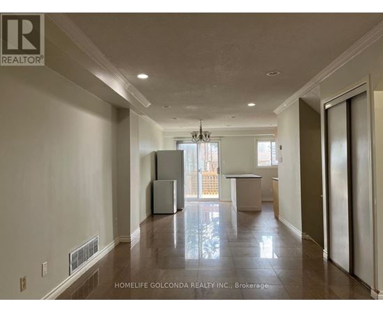 A spacious, empty room with a refrigerator and a table in the middle.