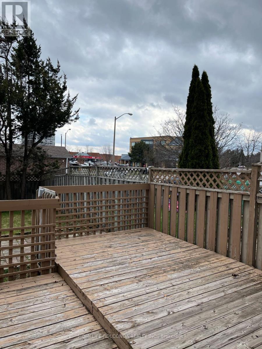 A wooden deck with a railing and trees in the background.