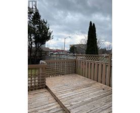 A wooden deck with a railing and trees in the background.