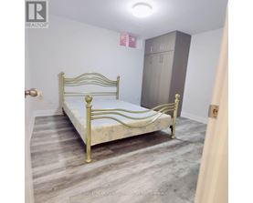A bedroom with a bed, wardrobe and a brokerage sign.