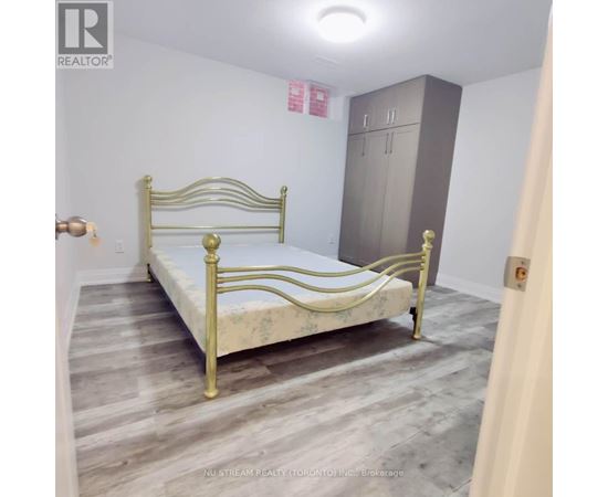 A bedroom with a bed, wardrobe and a brokerage sign.