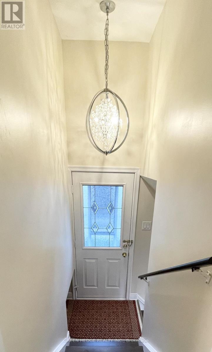 A hallway with a chandelier and a door with a glass window.