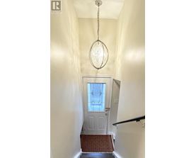 A hallway with a chandelier and a door with a glass window.