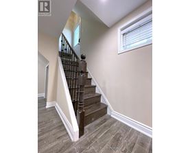 A staircase with a wooden handrail and a window.