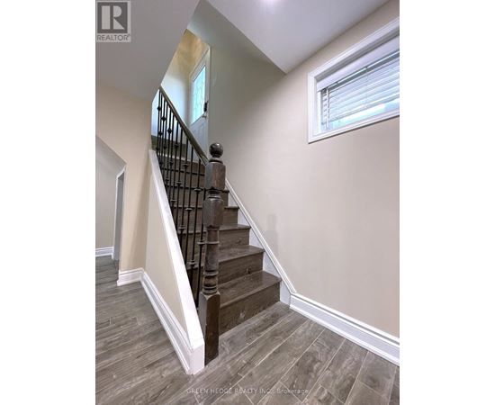 A staircase with a wooden handrail and a window.
