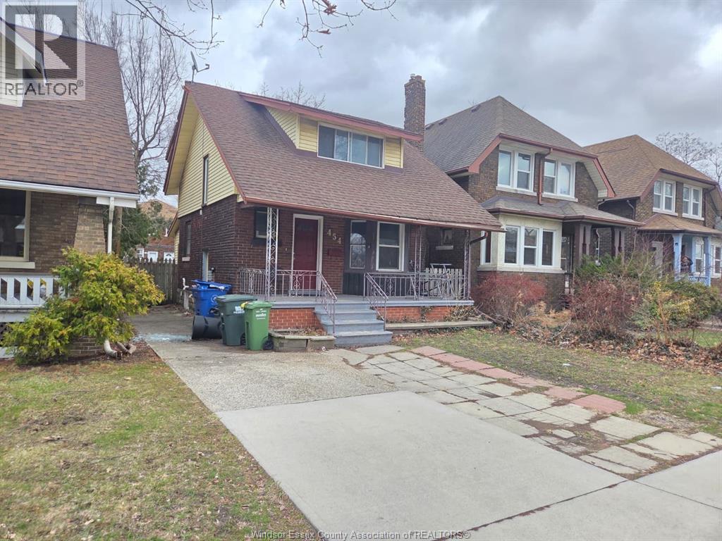 A house with a brown roof and a red door is surrounded by a white fence.