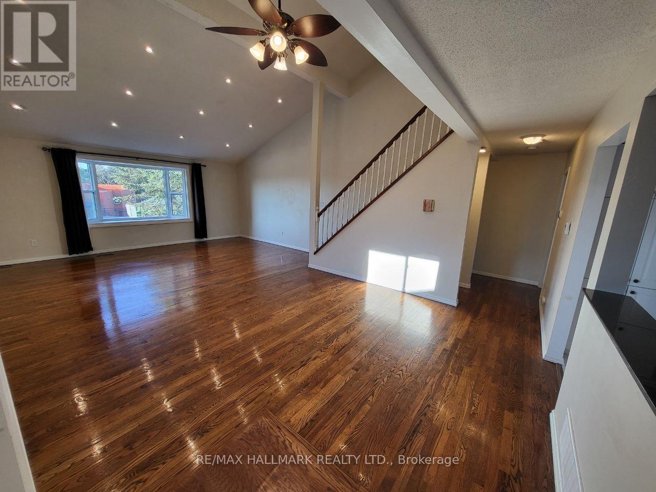 A spacious room with wooden flooring and a ceiling fan.