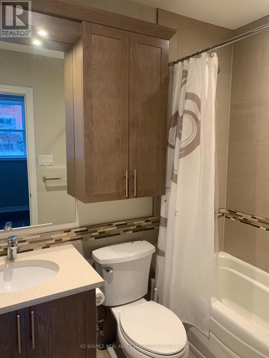 A white toilet sits in a bathroom with a wooden cabinet and a shower curtain.