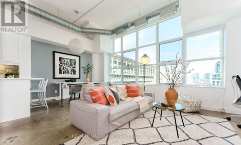 A living room with a grey couch and a black and white rug.