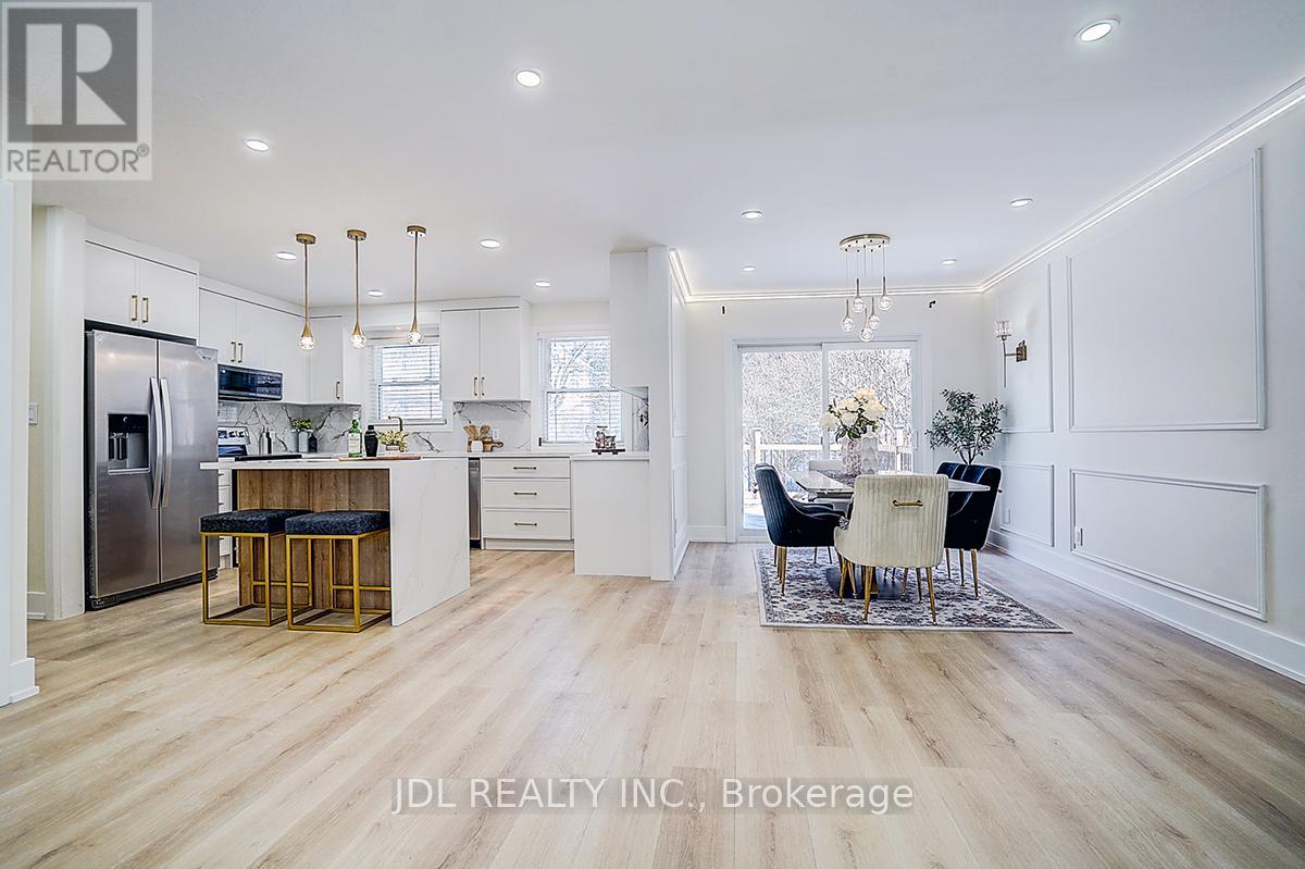 A modern kitchen with white cabinets and a wooden floor.