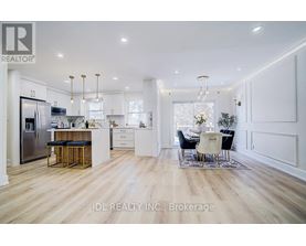 A modern kitchen with white cabinets and a wooden floor.