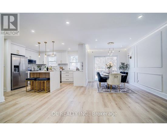 A modern kitchen with white cabinets and a wooden floor.