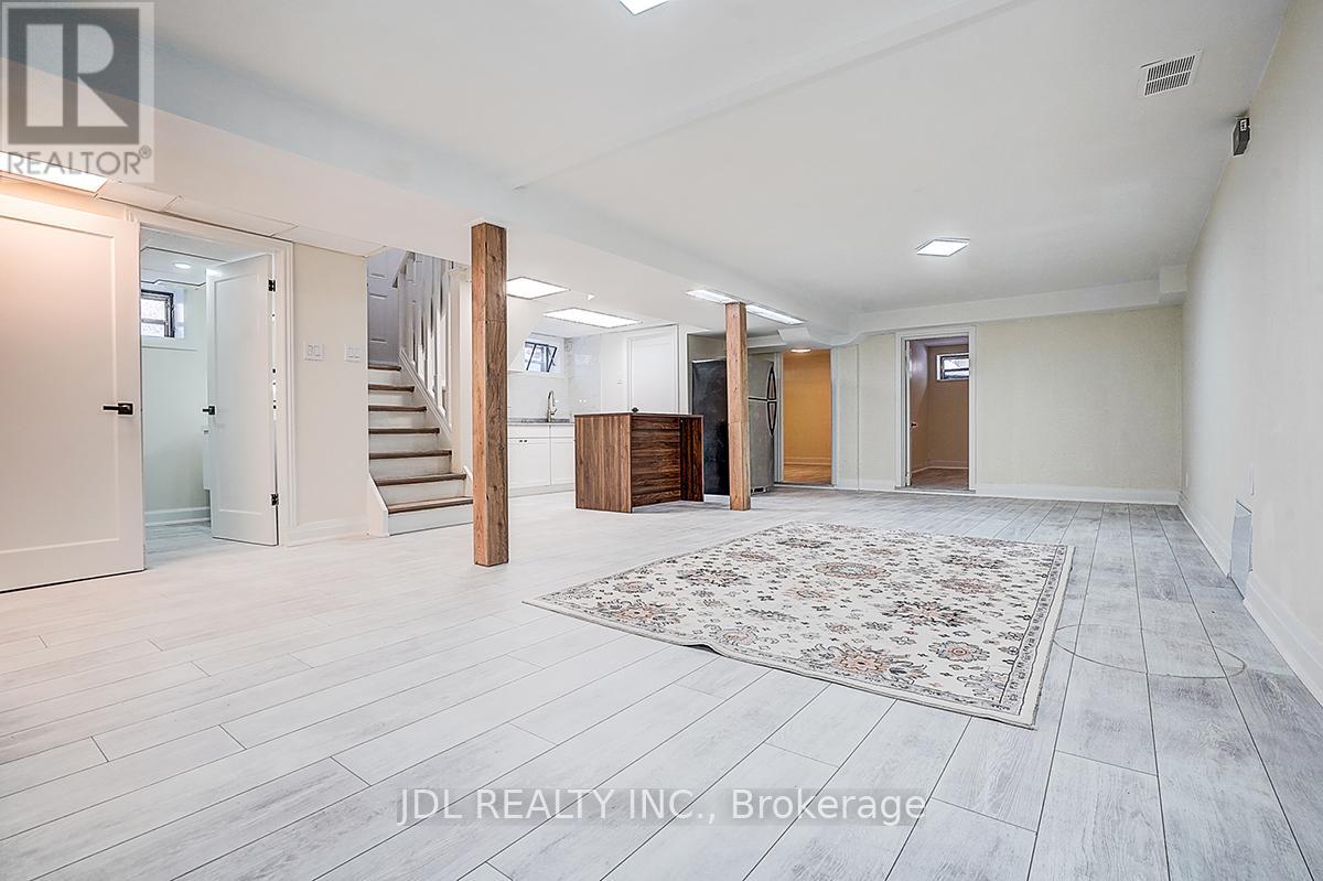 A spacious room with a staircase and a rug in the center.