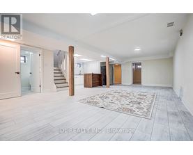 A spacious room with a staircase and a rug in the center.