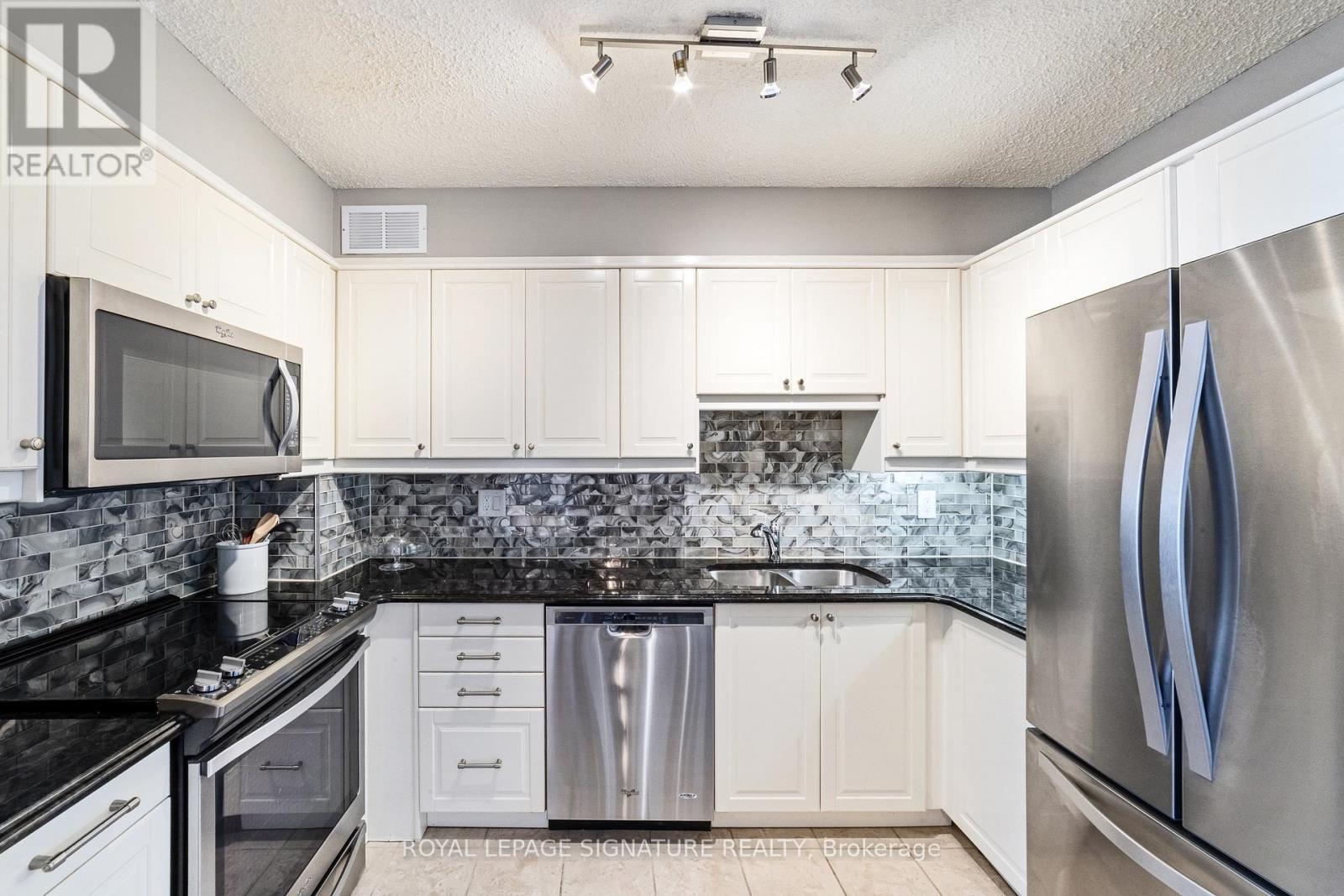 A kitchen with white cabinets and a black counter top.