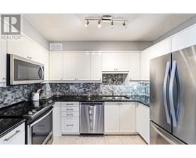 A kitchen with white cabinets and a black counter top.