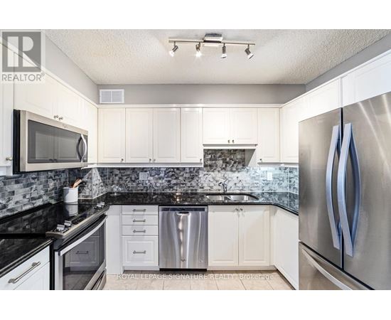 A kitchen with white cabinets and a black counter top.