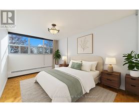 A bedroom with a large bed, a nightstand, and a window with a view of trees outside.