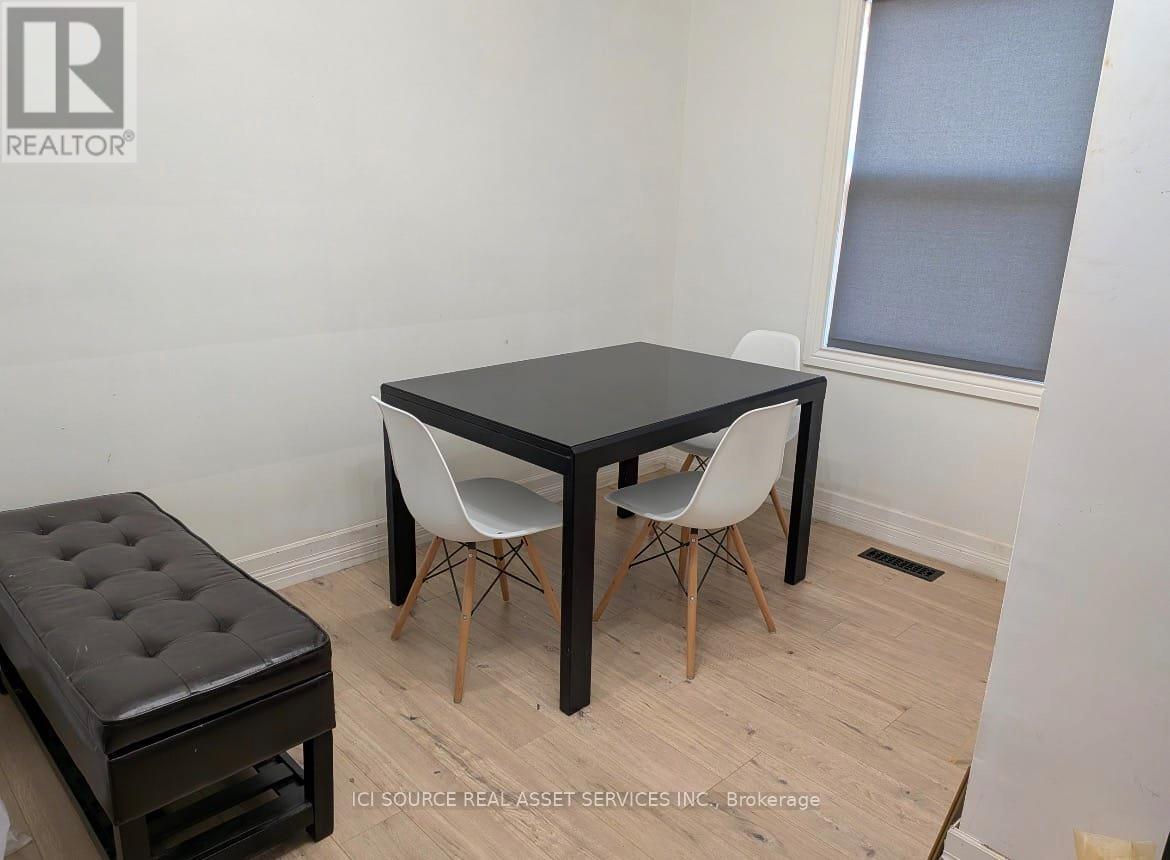 A black table with two white chairs and a black ottoman in a room.
