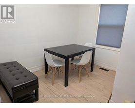 A black table with two white chairs and a black ottoman in a room.