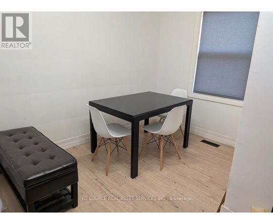 A black table with two white chairs and a black ottoman in a room.