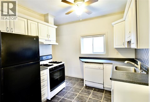 A black refrigerator stands next to a white stove in a kitchen.