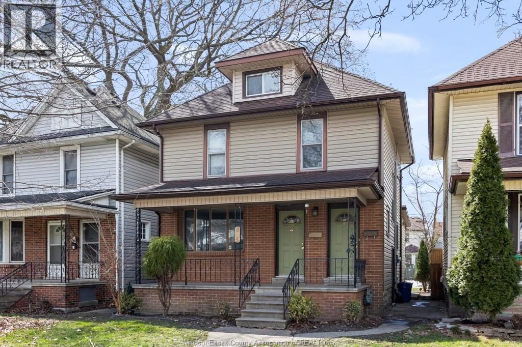 A house with a front porch and a tree in front.