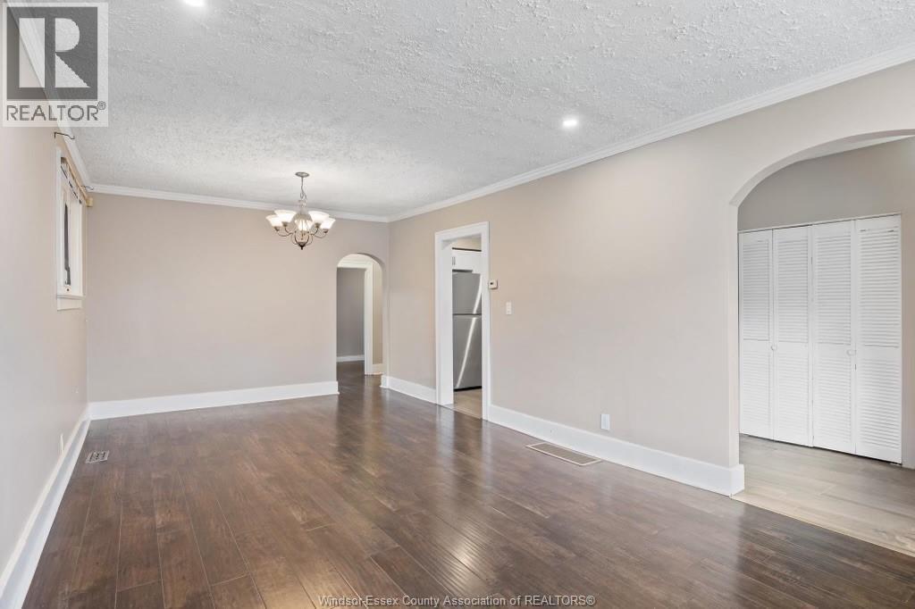 A room with wooden floors and white walls, with a doorway leading to another room.
