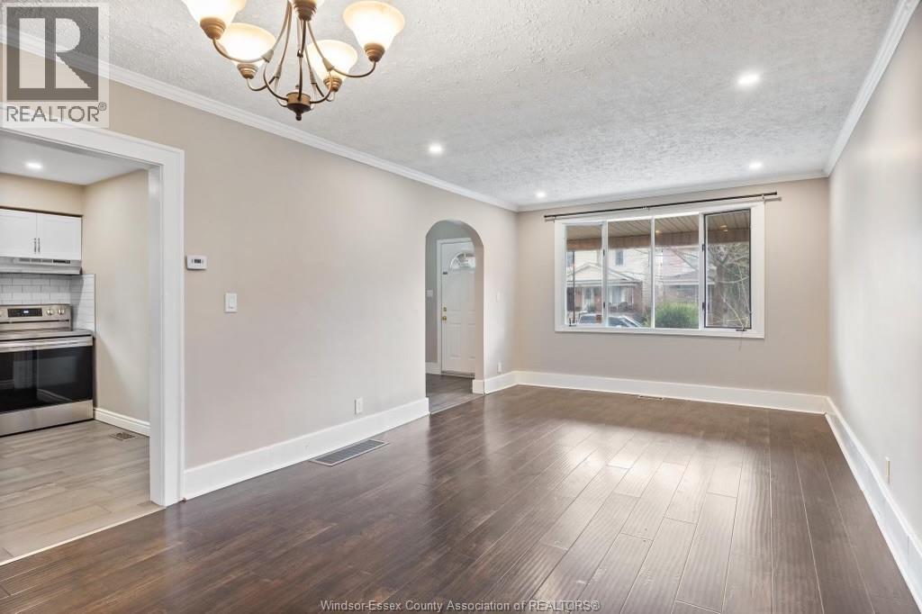 A spacious room with wooden flooring and a chandelier.