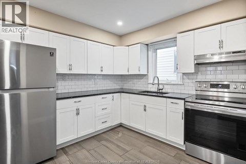 A kitchen with white cabinets and a stainless steel refrigerator.