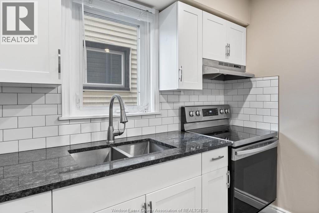 A kitchen with white cabinets and black countertops.