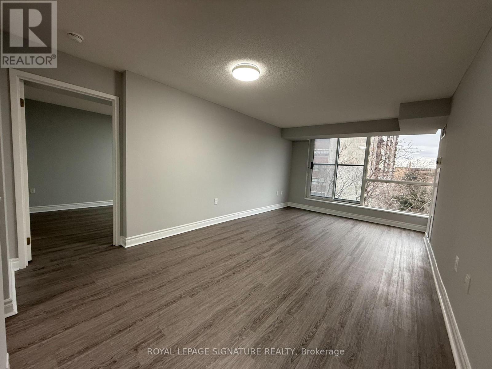 A room with wooden flooring and a window letting in light.