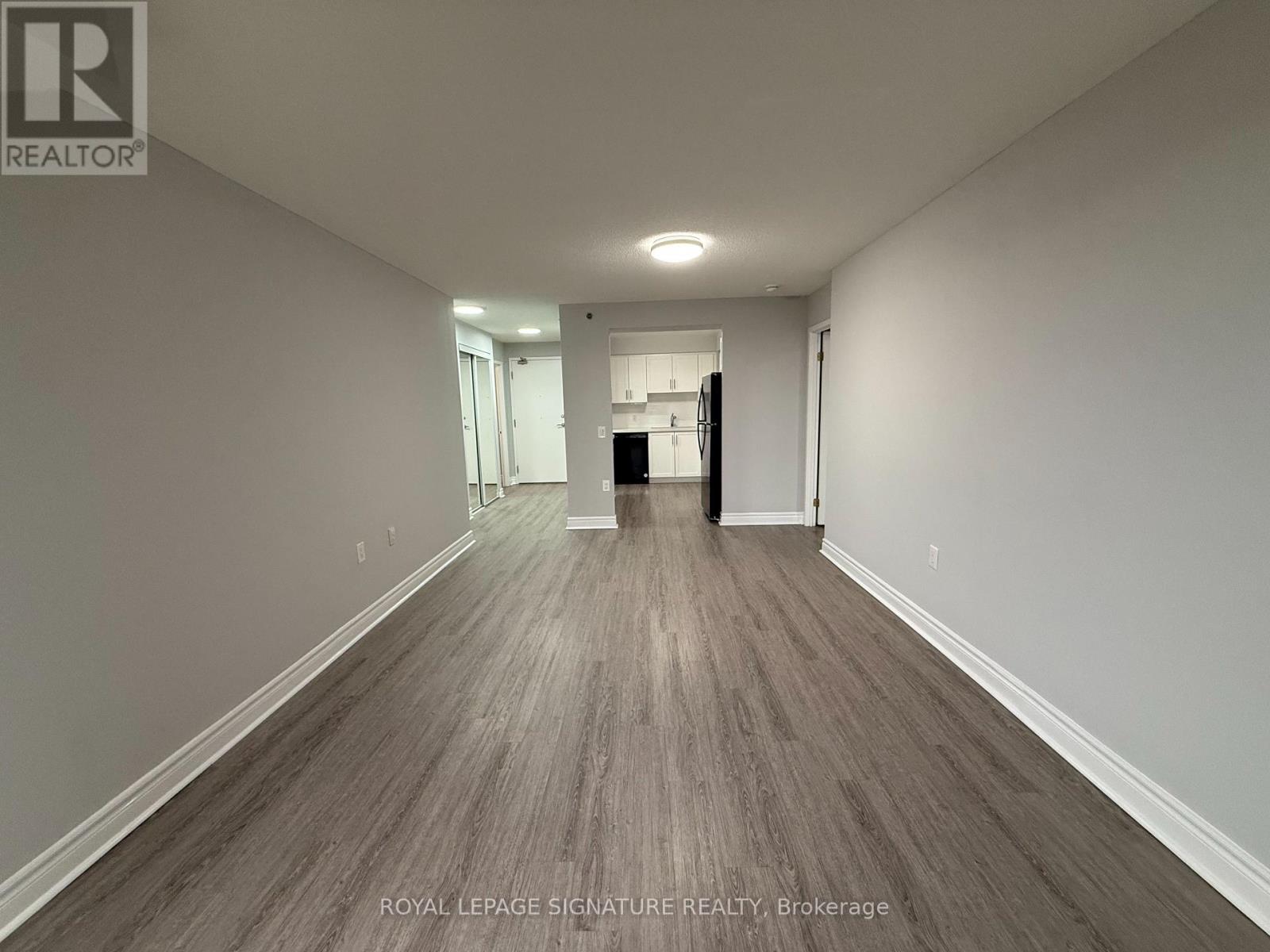 A long hallway with wood flooring and white walls.