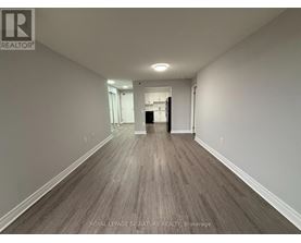 A long hallway with wood flooring and white walls.