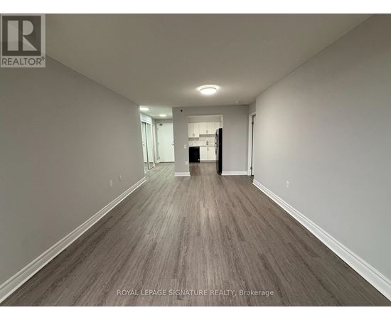 A long hallway with wood flooring and white walls.