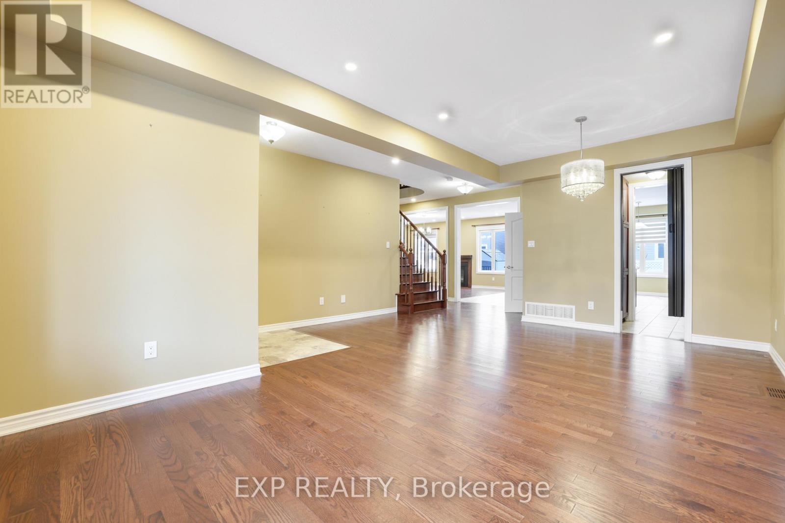 A spacious room with wooden floors and a staircase leading to another room.
