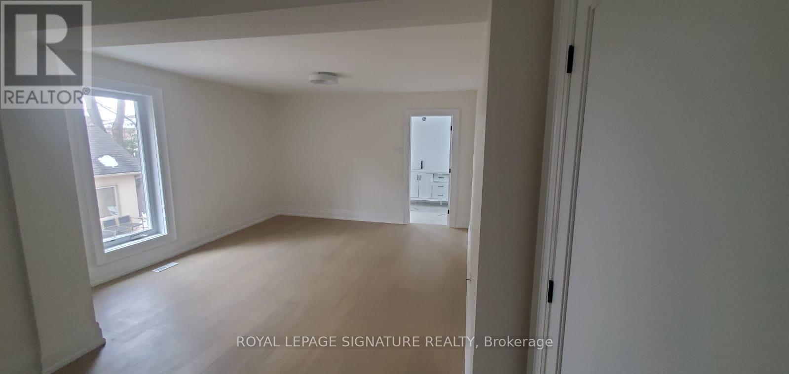 A white room with a window and a door leading to another room.