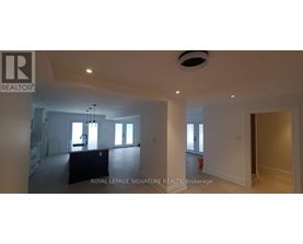 A large, empty room with a staircase on the left and a fire extinguisher on the right.