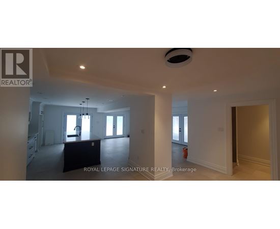 A large, empty room with a staircase on the left and a fire extinguisher on the right.