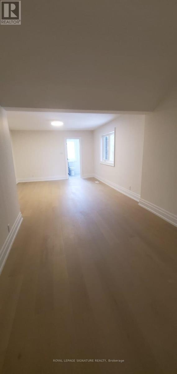 A spacious room with wooden flooring and white walls.