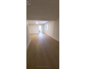 A spacious room with wooden flooring and white walls.