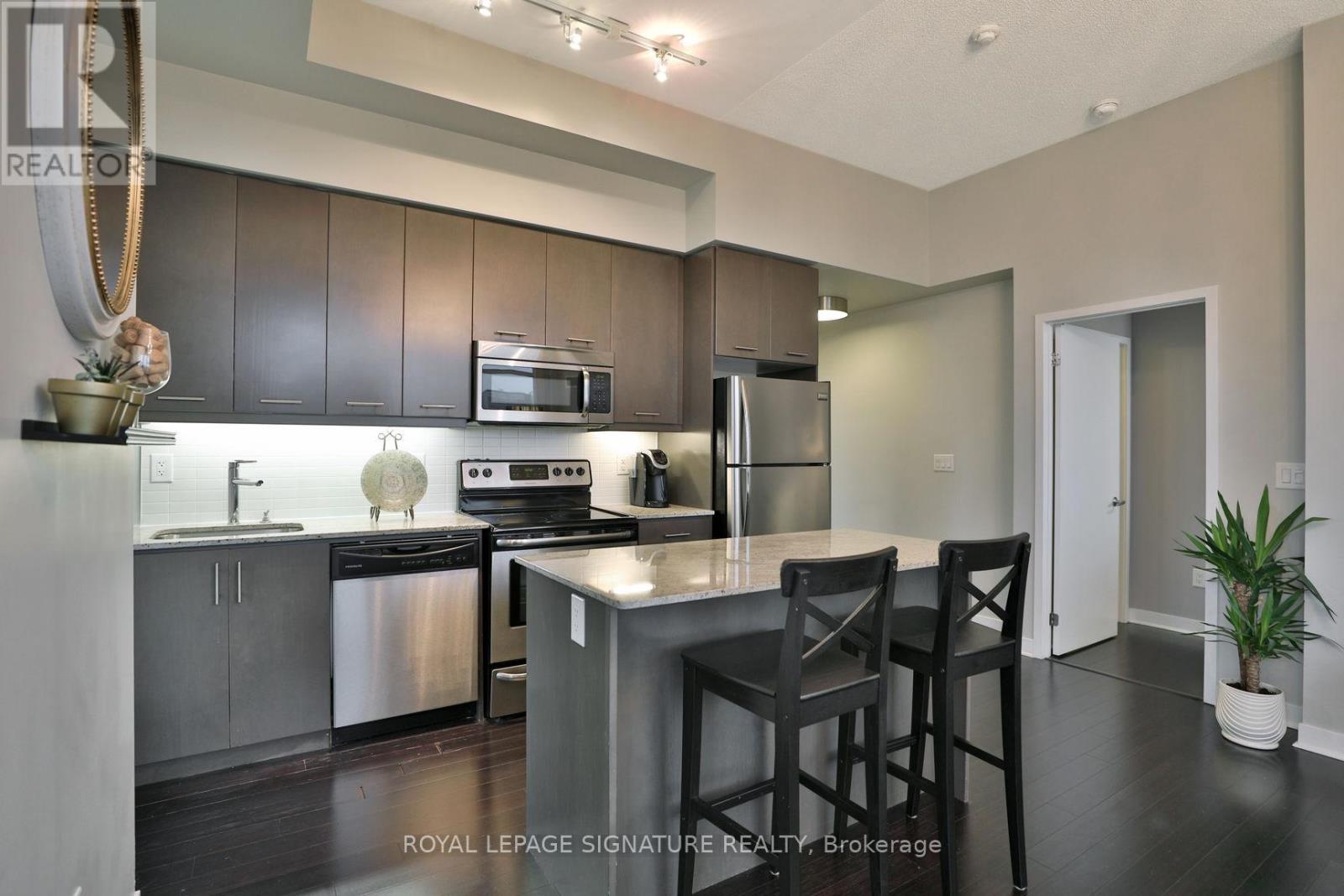 A modern kitchen with dark wood cabinets and stainless steel appliances.