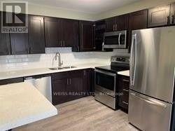 A kitchen with dark wood cabinets and stainless steel appliances.