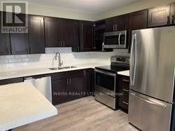 A kitchen with dark wood cabinets and stainless steel appliances.