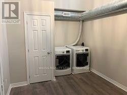 A room with a white door and two white ovens under a pipe.